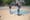 One woman doing a trick on a skateboard while another one watches at a park in Brooklyn.