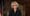 New York Chief Judge Janet Fiore in a still from her State of the Courts address, wearing glasses and pearl earings and a bla