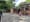 A woman walks a white fluffy dog in front of the Tompkins Square Park bathrooms on a summer day.
