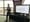 A facilitator stands in front of a flat screen TV with a word cloud, and speaks to participants at a "Visioning session" at C