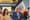 Adams looking sidelong at a table in City Hall in front of the New York State Flag